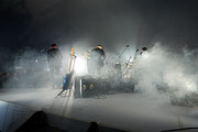 Photographie couleur du groupe The National, vu de dos, en train de jouer sur une scène pleine de fumée.